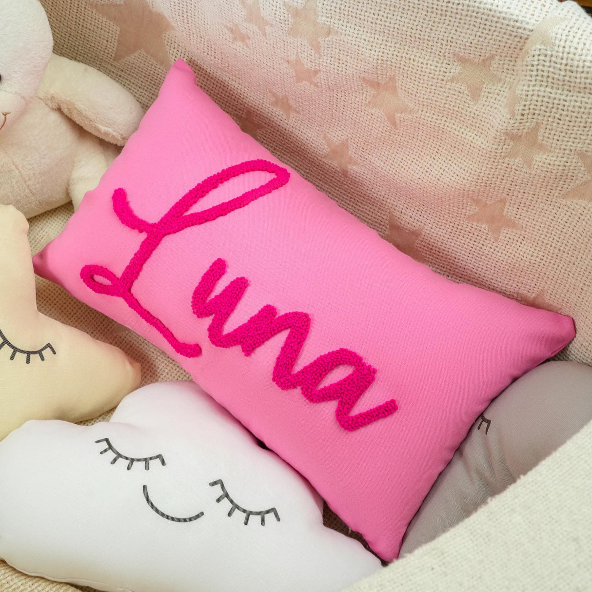 a pink pillow sitting next to a white stuffed animal