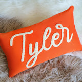 an orange pillow with the word tyler on it