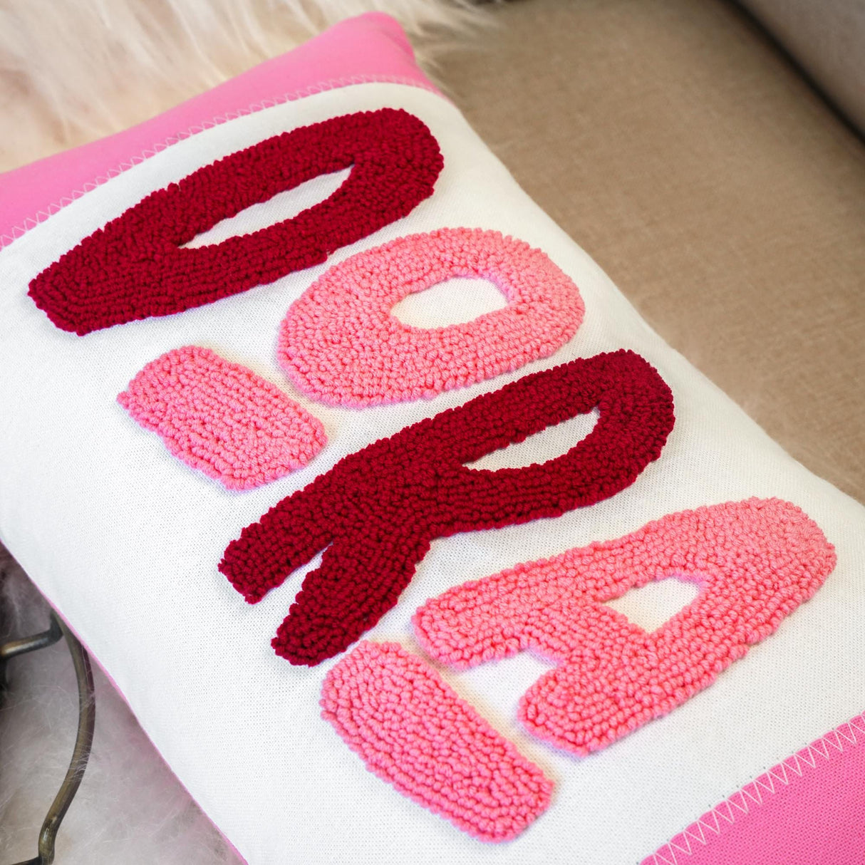 a pink and white pillow with the word boo on it