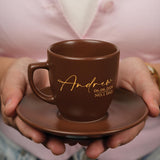 a person holding a coffee cup and saucer