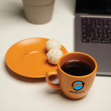 a cup of coffee next to a plate with a doughnut on it