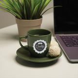 a cup of coffee sitting on a saucer next to a laptop