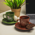 a cup of coffee next to a laptop on a desk