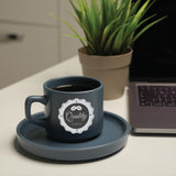 a coffee cup sitting on a saucer next to a laptop