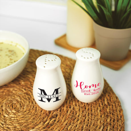 two salt and pepper shakers sitting on a mat next to a bowl of soup