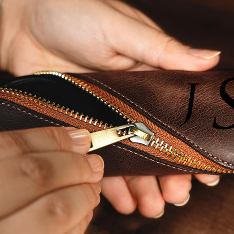 a person is holding a brown purse with a zipper