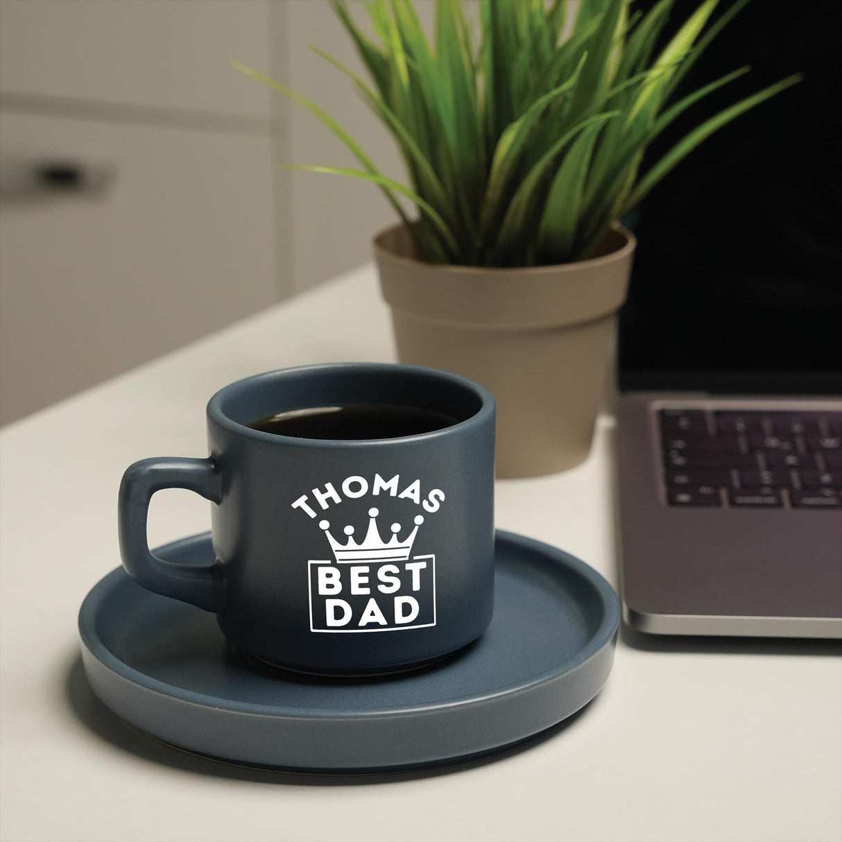 a coffee cup sitting on a saucer next to a laptop