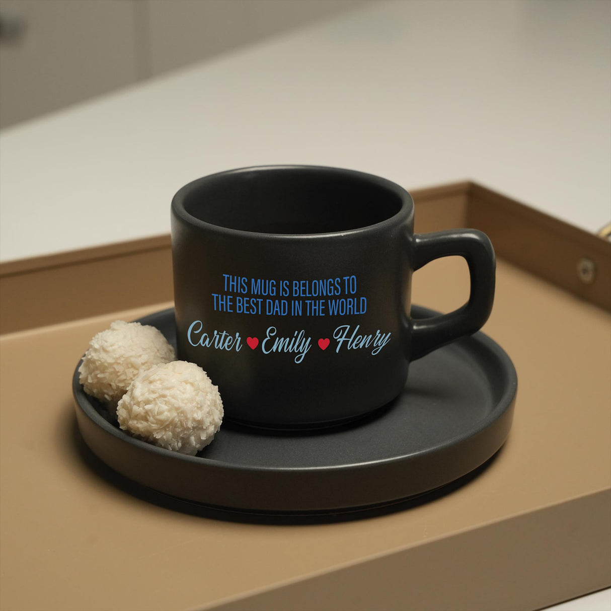 a black coffee cup and two white balls on a tray